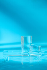 Glass podium in different shapes are displayed over blue background. Product presentation, mockup, show cosmetic product, Podium, stage pedestal or platform