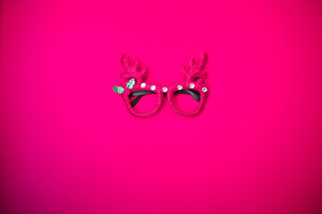 Christmas masquerade glasses with deer antlers on a pink background. The concept of a Christmas...