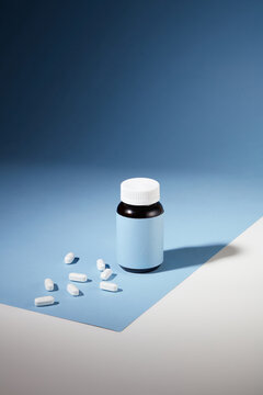 The white tablets are displayed with an unlabeled medicine bottle against a blue-white background. Medical concepts for advertising. Front view.