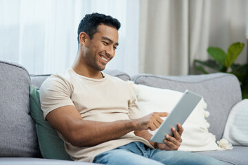 Tablet, smile and relax with a man on a sofa in the living room of his home for social media...