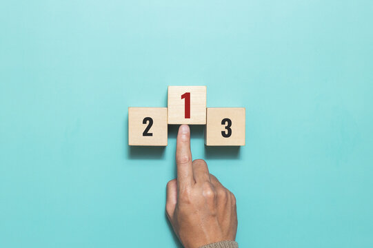 A man pushing wooden cube with the number one for task priority and management. Set work priority, arrange to do list. Concept of success,winner, victory or top ranking