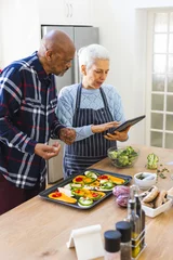  Diverse senior couple preparing healthy meal with vegetables using tablet in kitchen © WavebreakMediaMicro