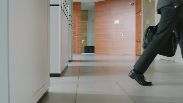 Low section side slowmo of two unrecognizable office workers coming off elevator in modern office