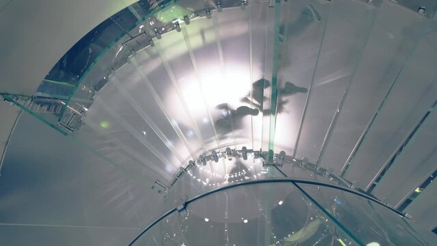 Rotating glass stairs and silhouettes of people - Powered by Adobe