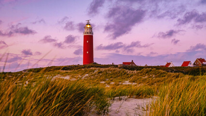 Texel lighthouse during sunset Netherlands Dutch Island Texel Holland during summer evening with sand dunes on the foreground - obrazy, fototapety, plakaty