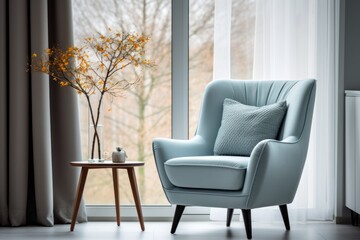 A mid-century blue armchair next to the window is decorated with white curtains. - obrazy, fototapety, plakaty