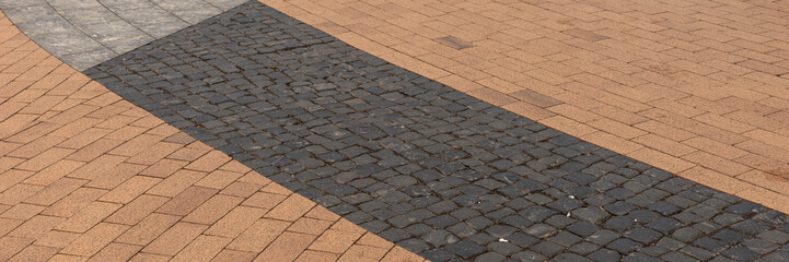 Fototapeta premium Panoramic image. New sidewalk in the city. Paving blocks made of colorful stones 
