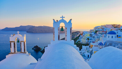 White churches an blue domes by the ocean of Oia Santorini Greece during sunset - obrazy, fototapety, plakaty