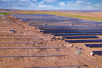 Elevated view of three workers installing solar panels in a new solar power plant in construction. Team of Workers Installing photovoltaic panels on a new solar power plant over an agricultural field