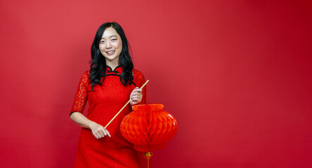 Asian chinese woman with red cheongsam or qipao holding denglong the paper lantern to wish the good...