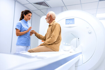Female radiologist or technician preparing senior man for complete MRI or CT head scan at oncology...