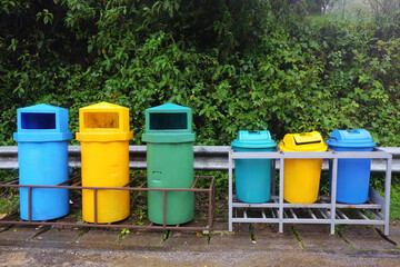 colorful plastic recycle bins Trash cans for garbage separation, Collection of waste bins of different types of garbage recycling, and separate waste collection in Tropical rain forest in Thailand