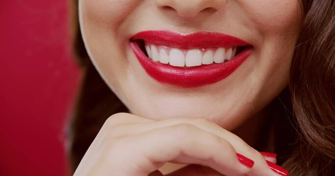 Closeup, red lips and woman with a smile, dental wellness and cosmetics on a red studio background. Person, girl and model with happiness, teeth whitening and veneers with confidence and aesthetic