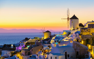 White churches an blue domes by the ocean of Oia Santorini Greece during sunset, a traditional...