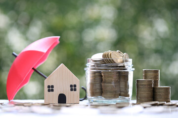 Protection, Model house and stack of coins money with the umbrella on nature green...