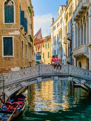 Fototapeta na wymiar a couple of men and women on a city trip in Venice Italy sitting at a bridge in Venice, Italy. cityscape citytrip Venice Italy during summer