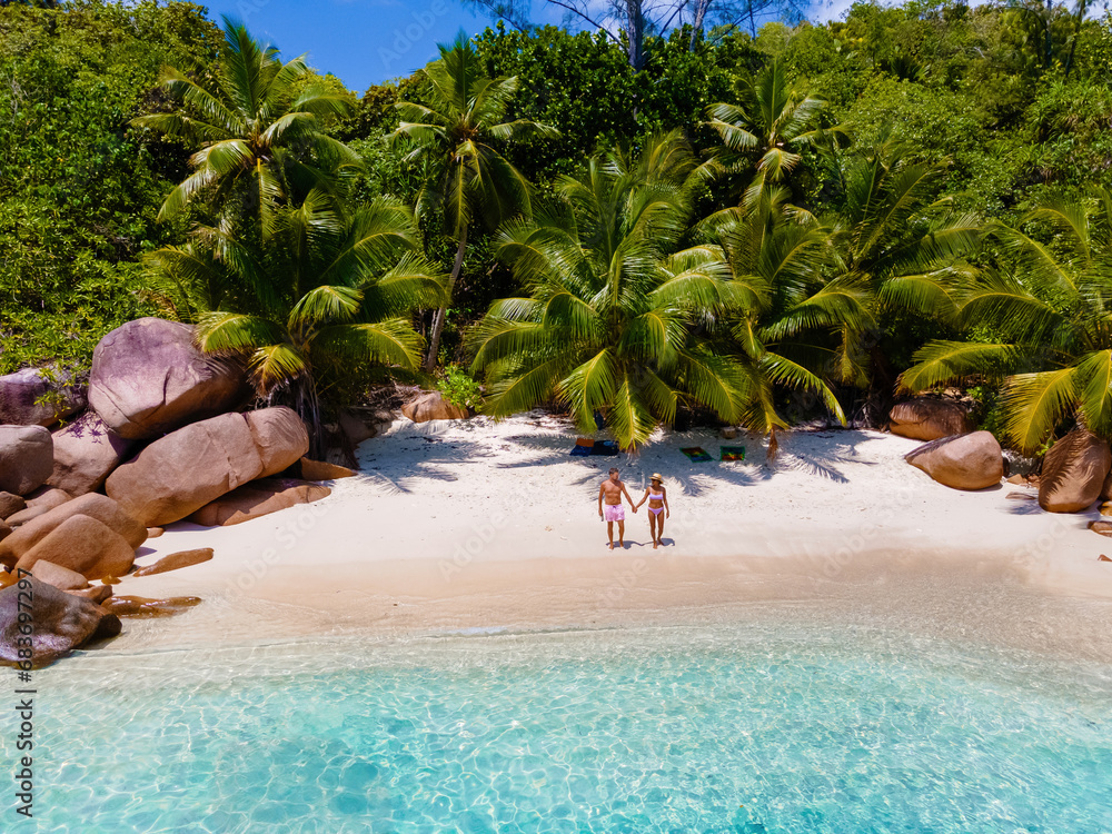 Wall mural Praslin Seychelles tropical island with white beaches and palm trees, a couple of men and women mid age on vacation at Seychelles visiting the tropical bay of Anse Lazio Praslin Seychelles.