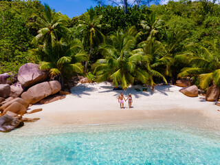 Praslin Seychelles tropical island with white beaches and palm trees, a couple of men and women mid age on vacation at Seychelles visiting the tropical bay of Anse Lazio Praslin Seychelles.