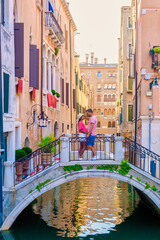 a couple of men and women on a city trip in Venice Italy sitting at a bridge in Venice, Italy. Architecture and landmark of Venice
