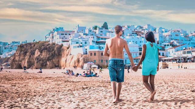 Happy young couple of men and woman walking at the beach of Albufeira Algarve Portugal Algarve during summer
