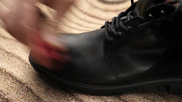 Black leather boots are cleaned with shoe cream. The concept of shoe care.