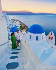Couple watching the sunset on vacation in Santorini Greece, men and women watching the village with...