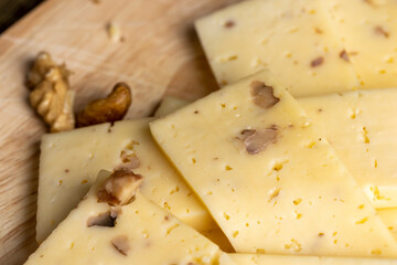 Sliced piece of milk cheese with walnuts