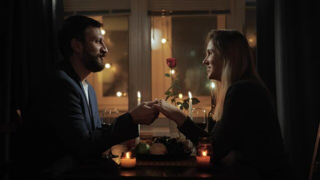 Date, Valentines Day, proposal. Romantic dinner, man and woman holding hands and talking excitedly, joking, laughing