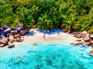 Praslin Seychelles tropical island with white beaches and palm trees, young men in swimwear at the beach on vacation at Seychelles visiting the tropical beach of Anse Lazio 