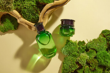 On a beige background, set of cosmetic mockup with green bottle and jar displayed with green moss...