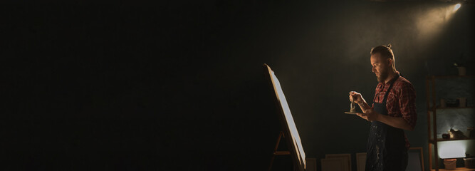 Artist working on abstract painting, create modern picture. Dark creative studio