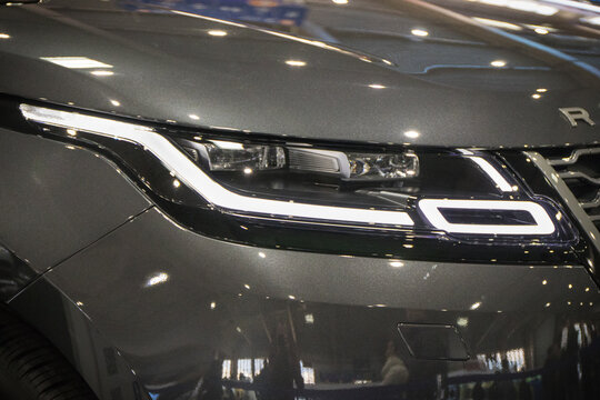Poznan, Poland - April 08, 2022: Poznan Motor Show. Front glowing lamps of gray Range Rover Velar. Detail and part of vehicle