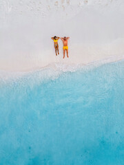 Drone top view of a couple of men and women lying down on the beach of Small Curacao Island, a...