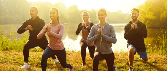 Group of fit and active people doing stretching exercising in nature. Happy smiling men and women in sportswear having sport workout in the park. Outdoors training and fitness concept. Banner.