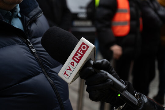 Reporter interview, holding microphone with logo sign of TVP Info television channel. Polish public broadcaster, state media TV station. News information network on November 23, 2023 in Krakow, Poland