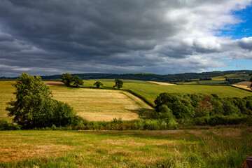 English fields of green countryside landscape with a dramatic high contrast cloudy sky 