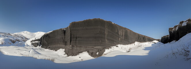 Wide angle panorama of the volcanic black wall near Gutansar mount in Armenia