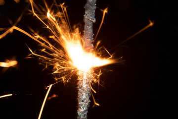 sparkler on a black background, sparks fly from a burning sparkler