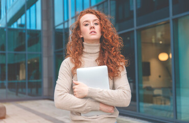 unhappy redhead woman holding a laptop and in shock from new in a city center