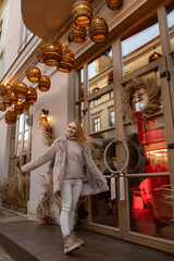 Fototapeta premium Happy young woman in fur coat amidst the festive atmosphere of Christmas on the city street. Christmas mood. Holiday weekend