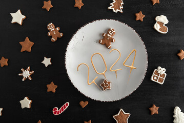 Top view Tasty glazed painted cookies on white plate: numbers 2024, stars and fir-tree. New Year...