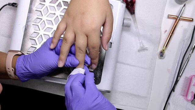 A manicurist treats a woman's cuticles with moisturizing wipe
