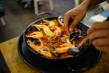 Typical spanish paella plate served by a waiter