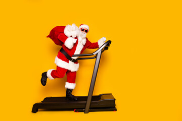Full body profile portrait of eccentric santa carry christmas presents bag run treadmill empty...