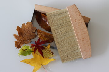 Kehrblech mit Herbstlaub und Handbesen