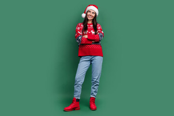 Full length photo of excited dreamy lady santa helper dressed print xmas sweater arms folded empty space isolated green color background
