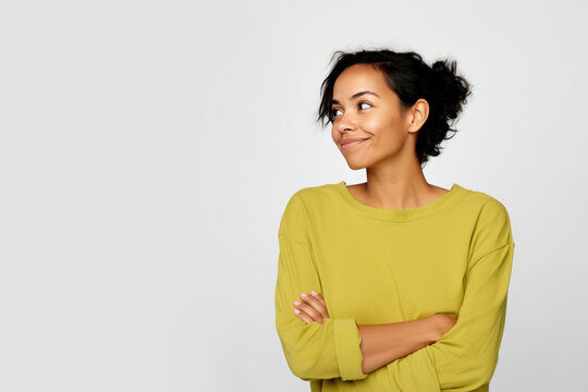 Jeune femme en train de penser en regardant sur le c&ocirc;t&eacute; vers le haut, espace libre pour du texte ou mise en sc&egrave;ne, tenue jaune fond uni gris p&acirc;le