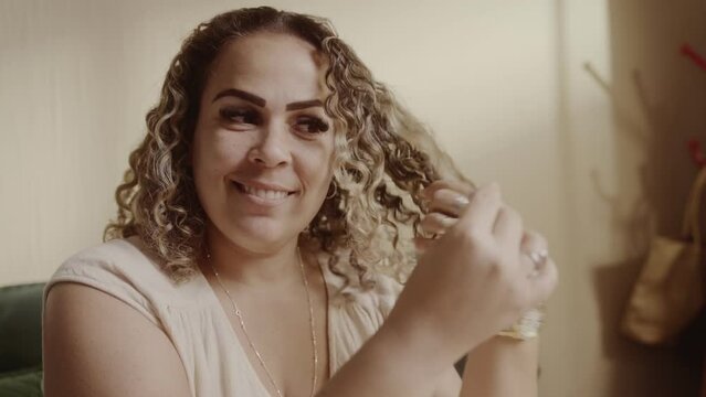 Mulher bonita, sorrindo, sentada na cama fazendo o cabelo pela manha. Cinematic 4k.