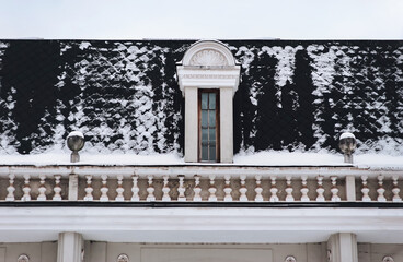 Black roof with attic and snow-covered tiled roof and white balustrade. Potocki Palace in Lviv,...