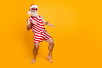 Full length photo of funny crazy elderly guy wear new year swimsuit hat sunglass dancing disco empty space isolated yellow color background